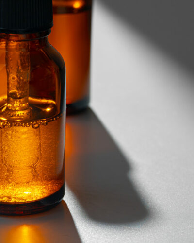 Amber glass bottles for cosmetics, natural medicine or essential oils on gray background, close up