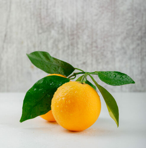 Fresh oranges with branch side view on white and grunge background